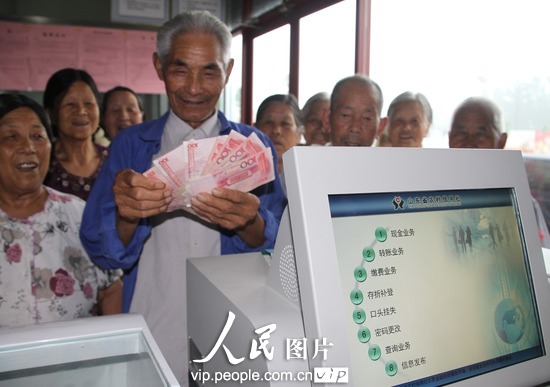 7月11日，在山东滨州市博兴县兴福镇李韩村，村民在“金融自助服务终端”设备前取款。