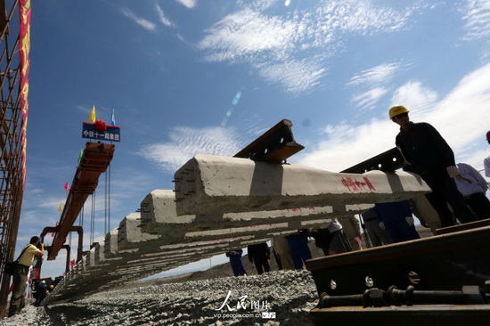 7月2日,工人在新疆哈密伊吾县淖毛湖红(红柳河)淖(淖毛湖)三(三塘湖)铁路建设工地铺设最后一组轨排。