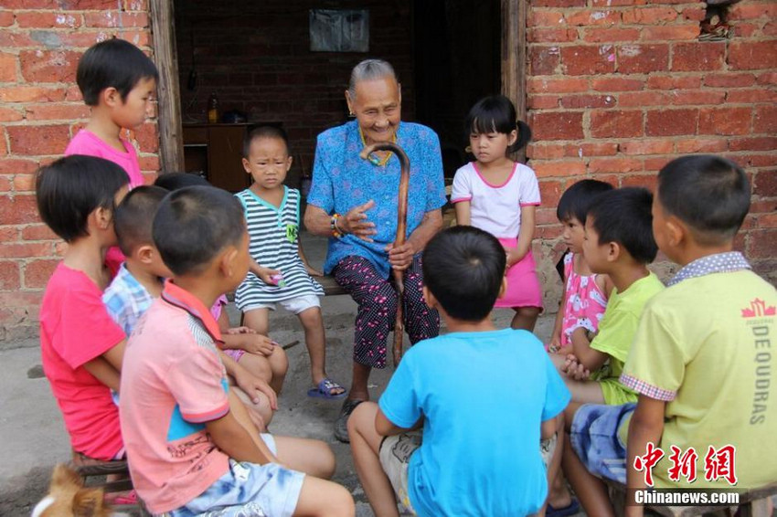 图为严金花给村里的留守儿童讲述自己的抗日故事。