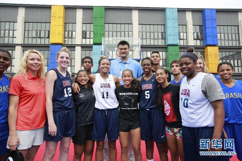 8月25日，姚明（中）在青奥村篮球场与各国运动员合影。
