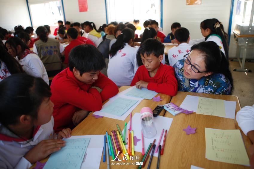 2014年9月1日，在龙泉中学临时活动板房学校的教室内，一名志愿者对学生进行心理辅导。