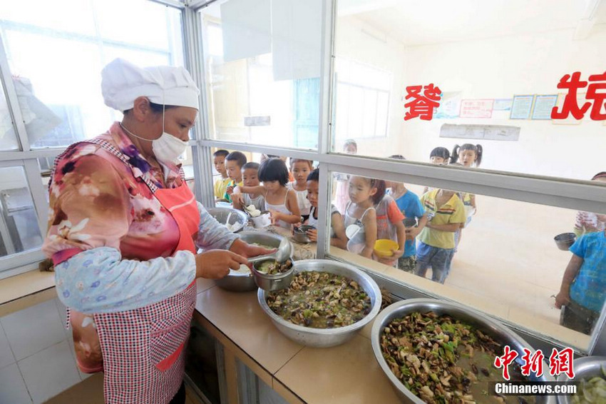 9月1日，在广西柳州市融安县大坡乡岗伟村小学食堂，工作人员在为学生加菜。