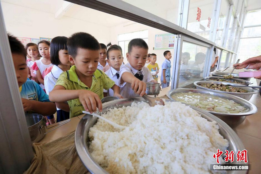 9月1日，学生们在广西柳州市融安县大坡乡岗伟村小学食堂根据自己的饭量排队盛取米饭。