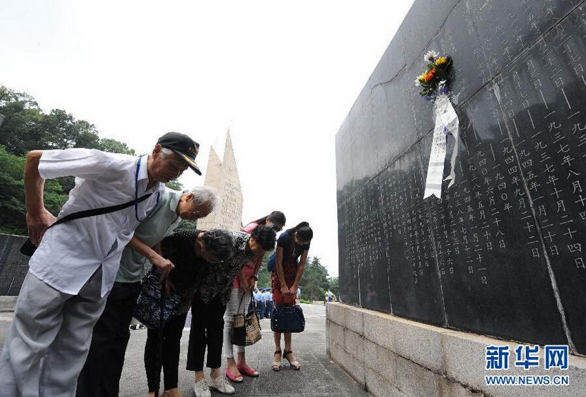 抗日航空烈士秦少亭的子女等亲属在刻有秦少亭名字的纪念碑前献花鞠躬。