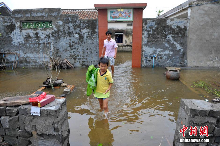 图为文昌市罗豆农场东溪村一位小朋友涉水走出家门。
