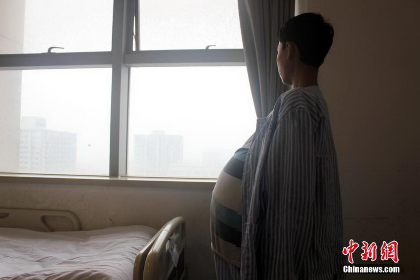 图为杨龙凯一个人站在窗边眺望远方，或许是受大肚子影响，他显得有些自闭，“我就是想做一个普通人。”