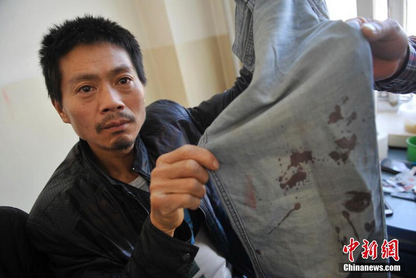 图为死者周秀云的丈夫王友志展示与民警发生冲突后沾满血迹的裤子。
