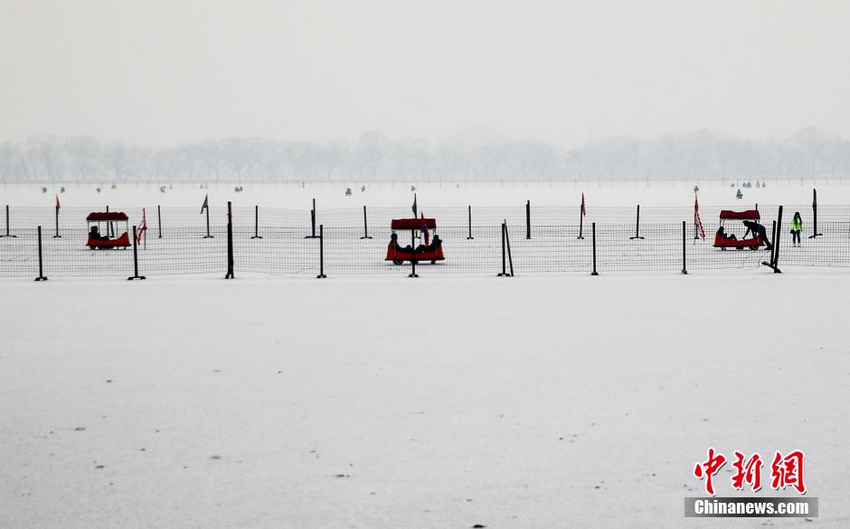 1月14日，游客在北京颐和园里滑冰车，昆明湖上蒙上了2015年北京第一场雪，雾霾却将雪景掩盖，远处的景色难以辨清。当日，北京空气陷入重度污染。