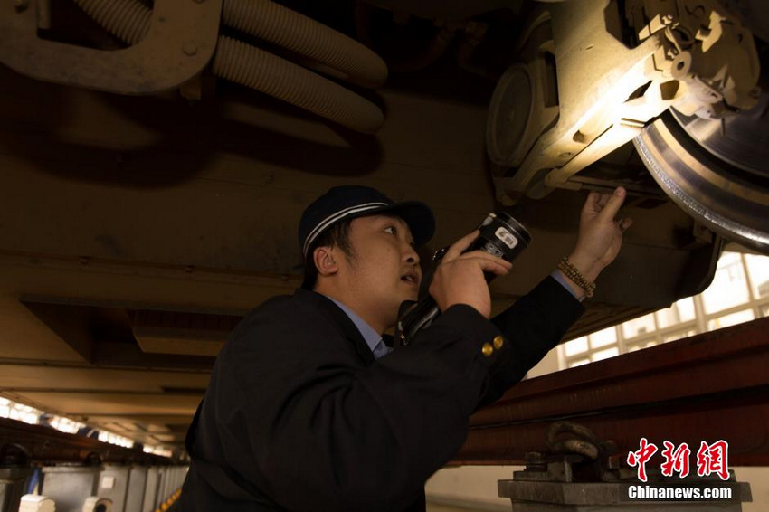检修地沟里，地勤机械师拿着手电筒对动车组进行一级检修作业。