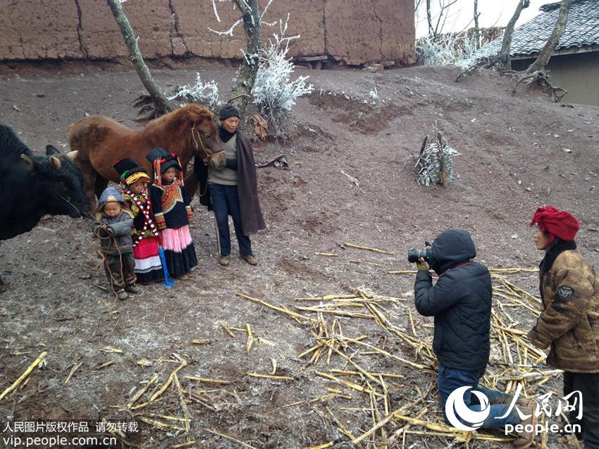 2014年12月11日，四川大凉山，由于拍摄需要，赵明跪在地上为村民拍摄全家福。