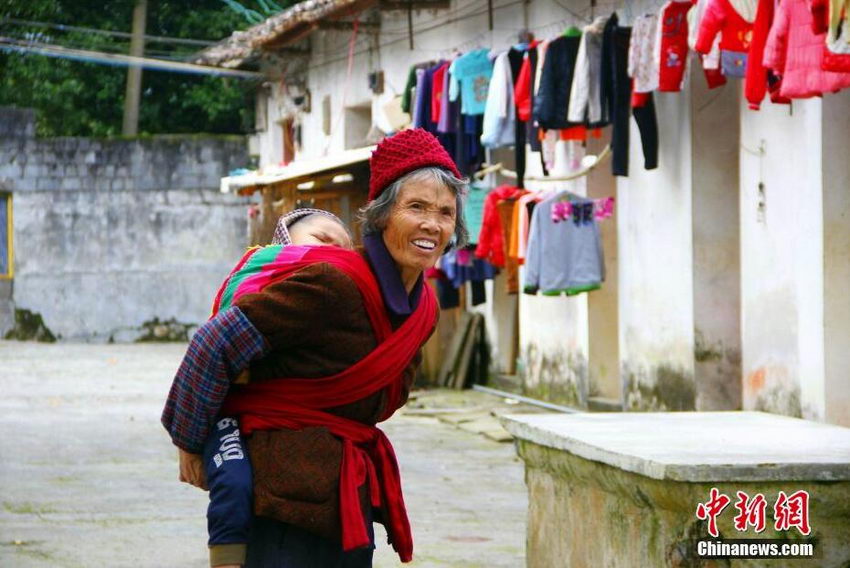 12月3日，在广西柳江县土博镇二中，老人正在照看孩子。