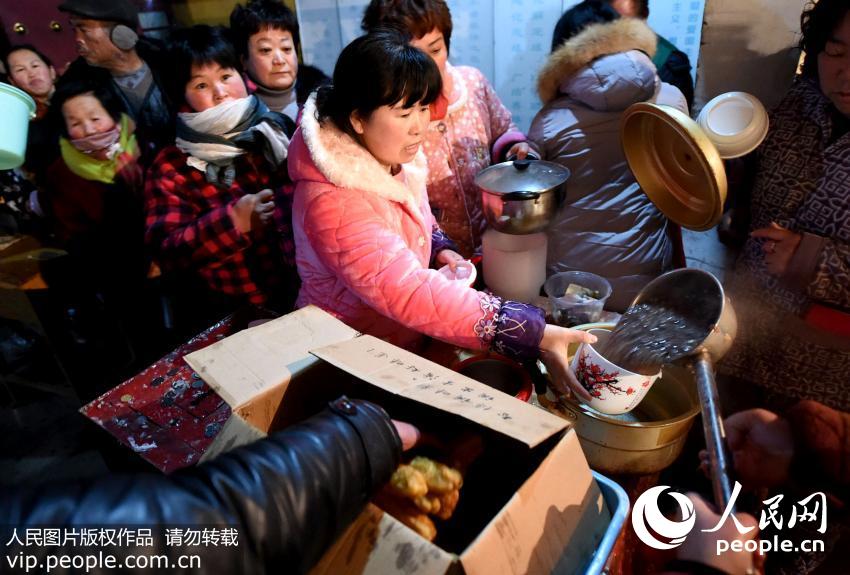 2016年1月17日,中国传统节日“腊八节”, 民间有喝腊八粥的习俗,安徽省亳州市白依律院内热气腾腾,义工将用红枣、莲子、大米、桂圆等多种原料熬制的腊八粥免费向市民发放,在寒冬里为人们送上传统美食以及腊八节的祝福。据寺院师傅介绍,寺院准备了一万份腊八粥,保障每位来领粥的市民都能喝上腊八粥。(刘勤利/人民图片)