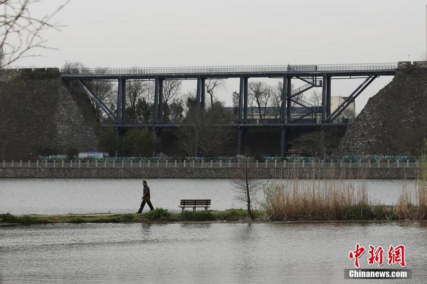 3月24日，市民从嫁接了一座轻钢结构人行天桥的南京六百岁明城墙前湖段前的道路上经过。