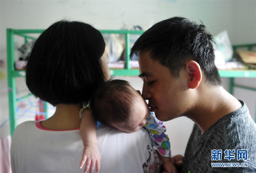 7月12日，宣城市宣州区双桥镇隆兴村的曹桂能在宣城市12中的安置点小单间内亲吻自己出生45天的女儿。为了让宝宝健康地生活成长，安置点的工作人员为他们腾出了一个小单间并发动网上力量捐来了奶粉和婴儿衣物。