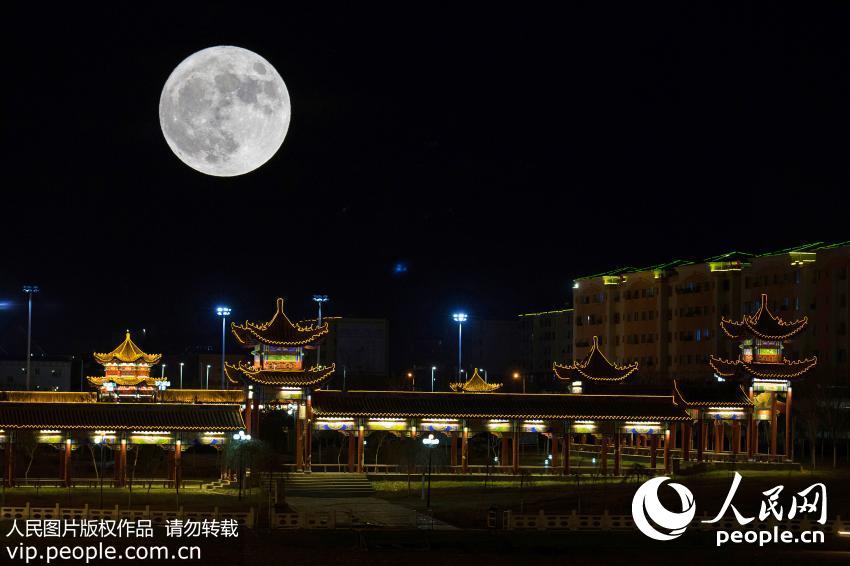 11月14日，新疆哈密巴里坤县，一轮圆月从城市上空升起。（张建刚/人民图片）