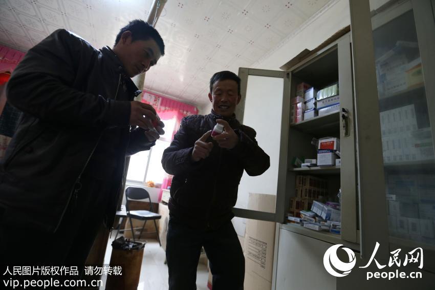 2017年2月6日，宁夏西吉县新营乡二府营村村医牟天明为患者取药。