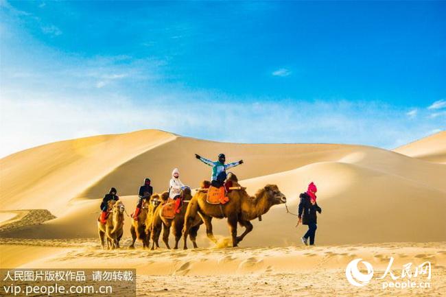 2017年12月12日，游客骑骆驼畅游冬季鸣沙山。