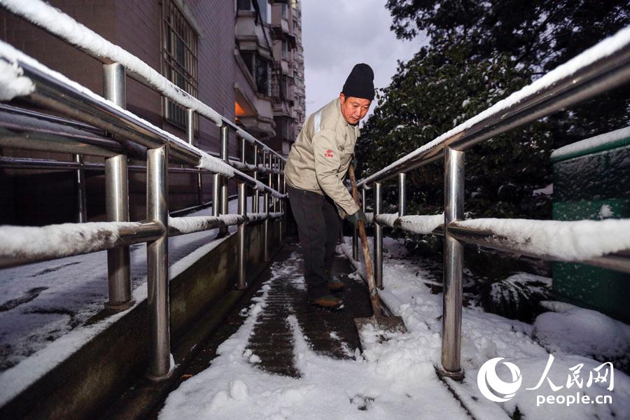 上海宝山的物业人员清晨铲除路面积雪，保障市民出行安全。
