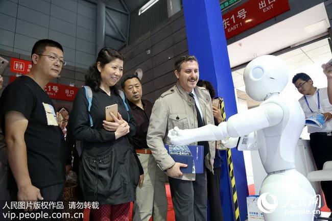 2018年5月27日，在合肥滨湖国际会展中心，外国友人对智能机器人产生了浓厚的兴趣。