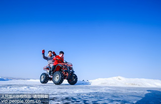 2018年12月23日，在新疆呼图壁县园户村镇鸭子湖冬季旅游景区，游客正在体验雪地摩托车。