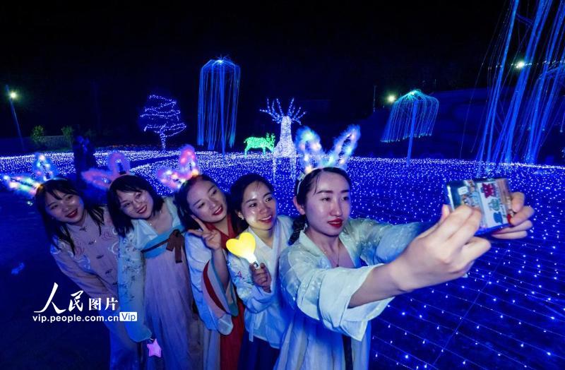 2021年4月29日夜晚，在安徽省宁国市港口镇西村，身穿汉服的游客们在灯光秀场内拍照打卡，各类主题场馆成为网红西村又一新地标。